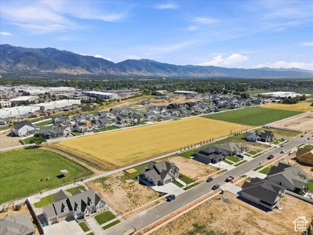 Expansive residential development featuring modern residences, undeveloped land parcels, surrounding commercial structures, and distant mountains