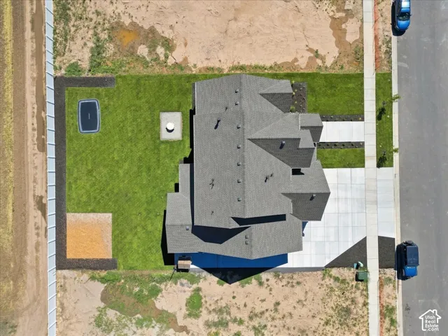 Asphalt shingle roof, concrete driveway, concrete sidewalk, fenced property perimeter, and manicured lawn