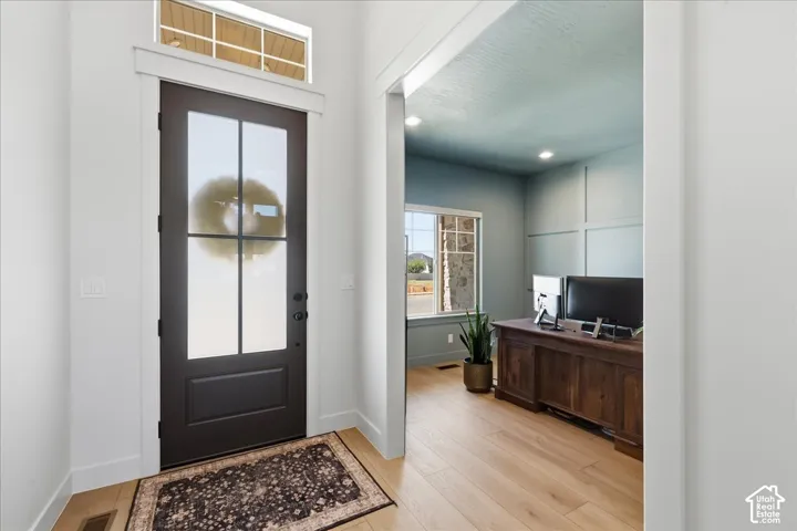 Entryway featuring a dark paneled door with transom window and light wood-finish flooring