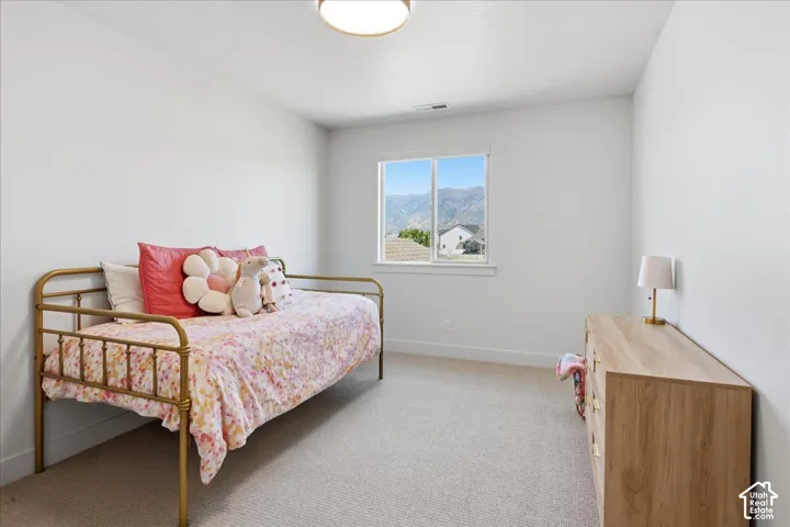 Expansive window framing mountain scenery, plush carpet flooring, recessed lighting, and crisp white walls
