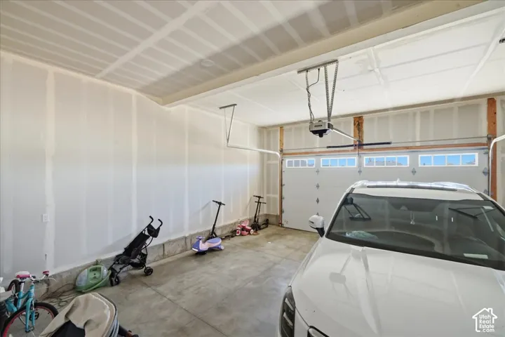 Attached garage featuring a concrete floor, two garage doors with upper window panels, and an automatic garage door opener