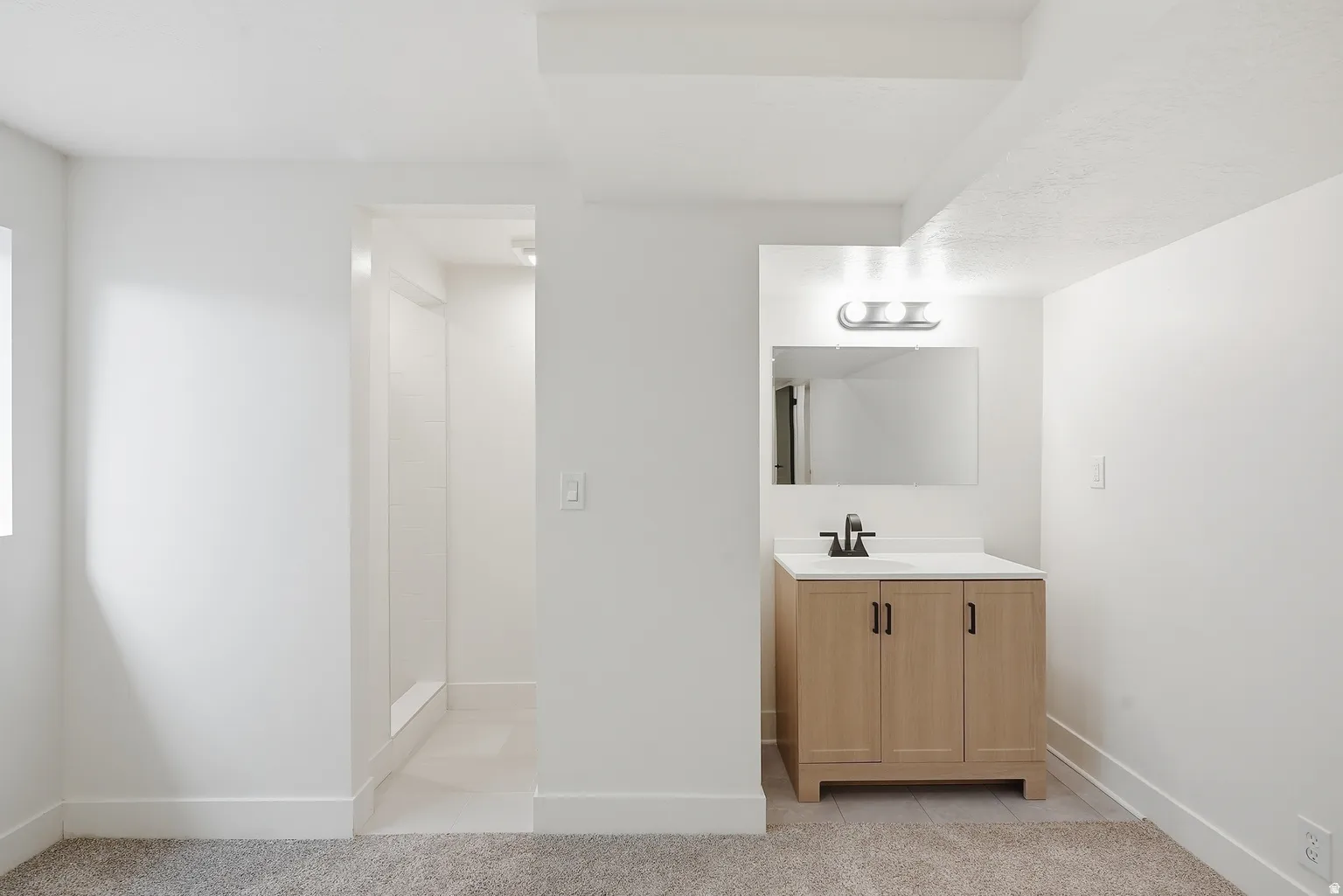 Bathroom vanity with a wood-finish cabinet, white countertop, and matte black faucet