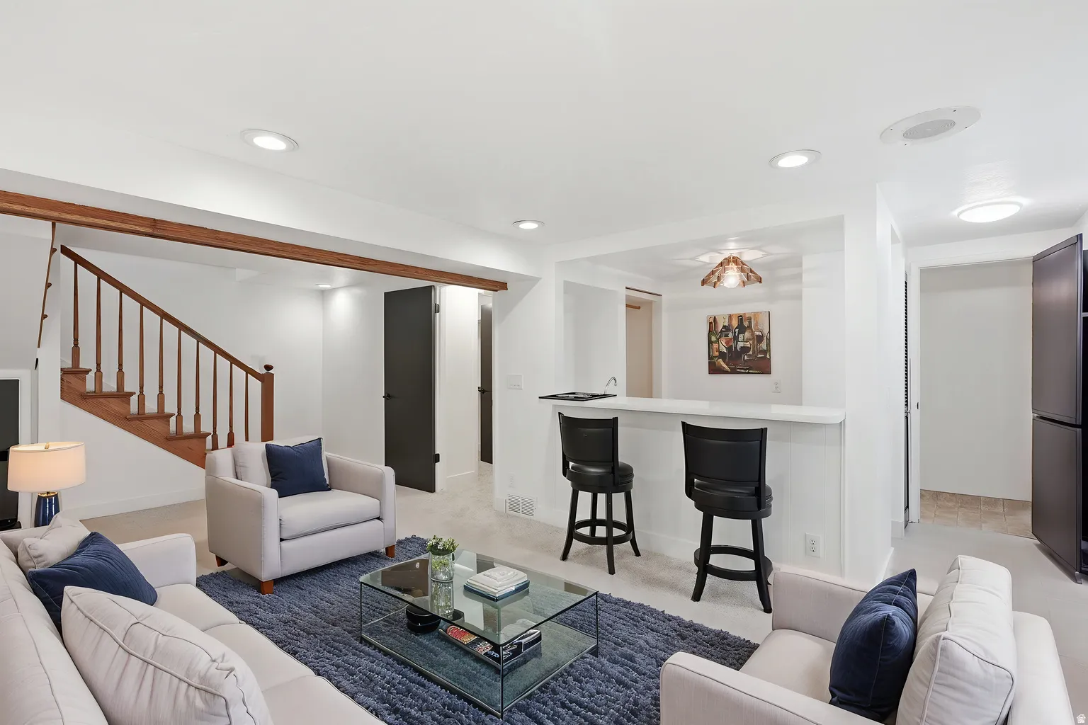 Recessed lighting throughout, a wood-finish staircase with balusters, a built-in wet bar, and a dedicated refrigerator alcove