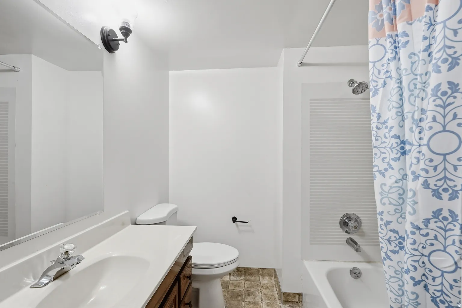 White vanity with integrated sink, chrome faucet, and mirrored medicine cabinet