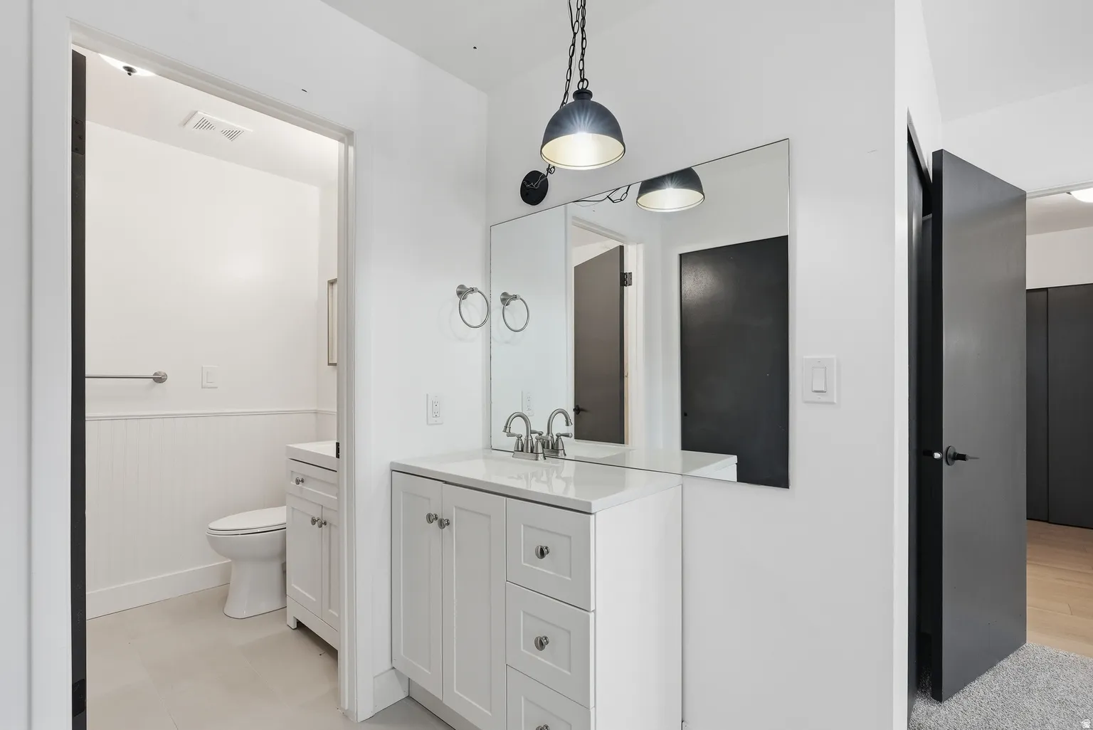 White vanity with a solid surface countertop, undermount sink, and polished chrome faucet