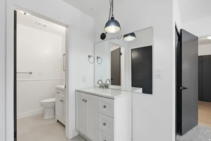 White vanity with a solid surface countertop, undermount sink, and polished chrome faucet