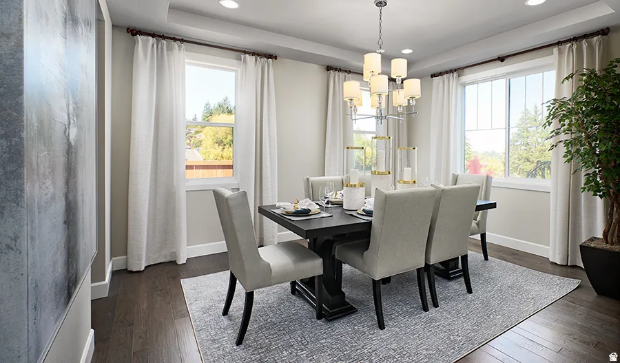 Recessed lighting, wood-finish flooring, two large windows, tray ceiling, and a prominent chandelier