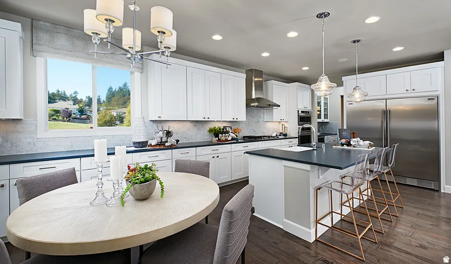Open-concept kitchen with white shaker cabinetry, stainless steel appliances, dark countertops, and wood-finish flooring