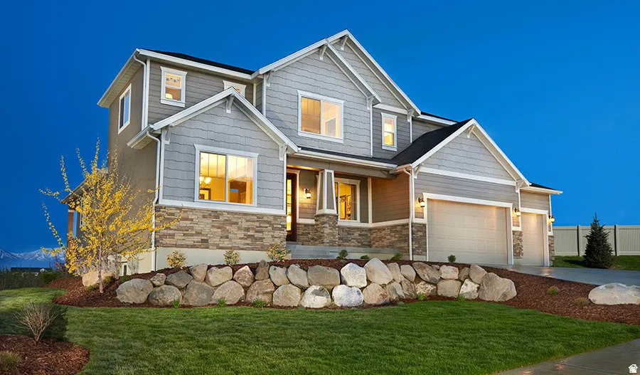 Two-story residence featuring a combination of horizontal siding and shake siding, stone veneer accents, and a dual-bay garage