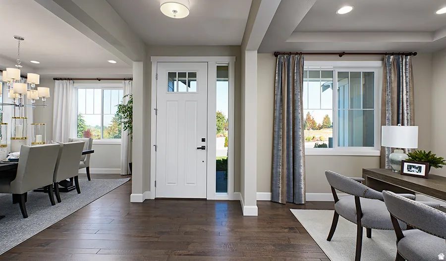 Wood-finish flooring throughout, solid panel front door with upper lites and sidelite, recessed lighting, and a tray ceiling