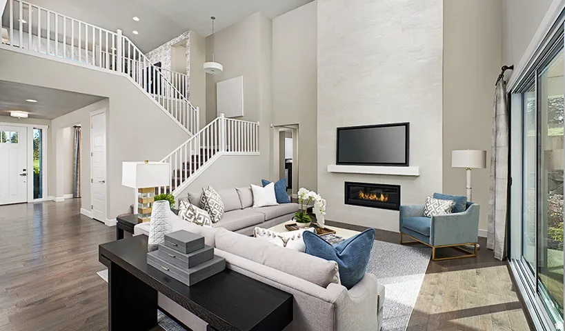 Two-story living area with wood-finish flooring, a contemporary fireplace, and an expansive sliding glass door