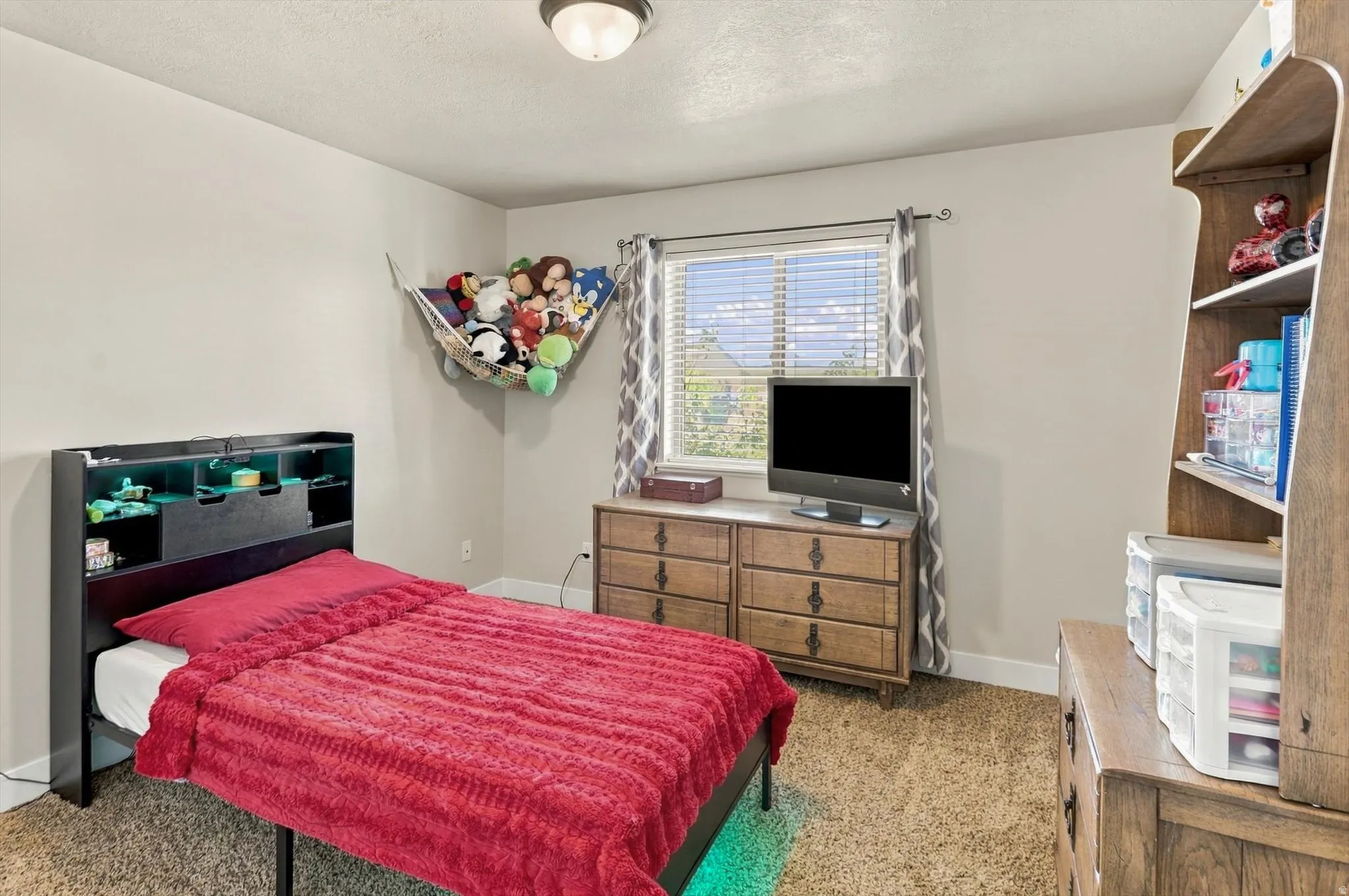 Carpeted room featuring a window with horizontal blinds, a ceiling-mounted light fixture, and neutral wall tones
