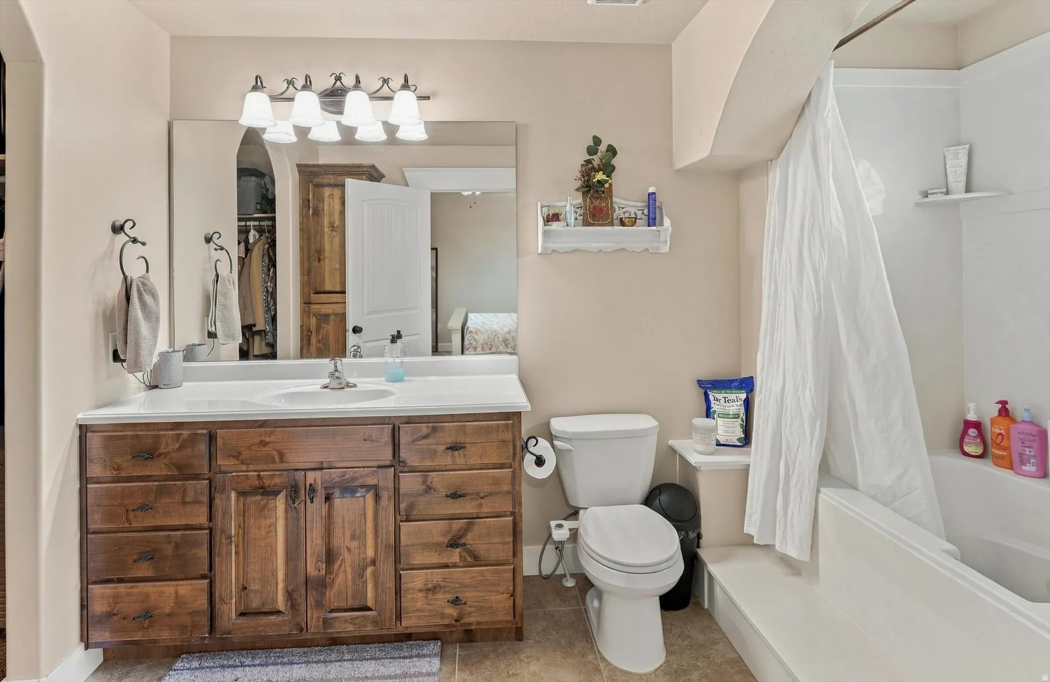 Bathroom featuring a vanity with wood-finish cabinetry, a single basin sink, and a combination shower-tub