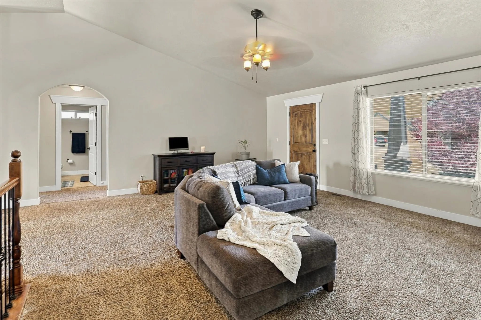 Carpeted room with vaulted ceiling and a decorative chandelier