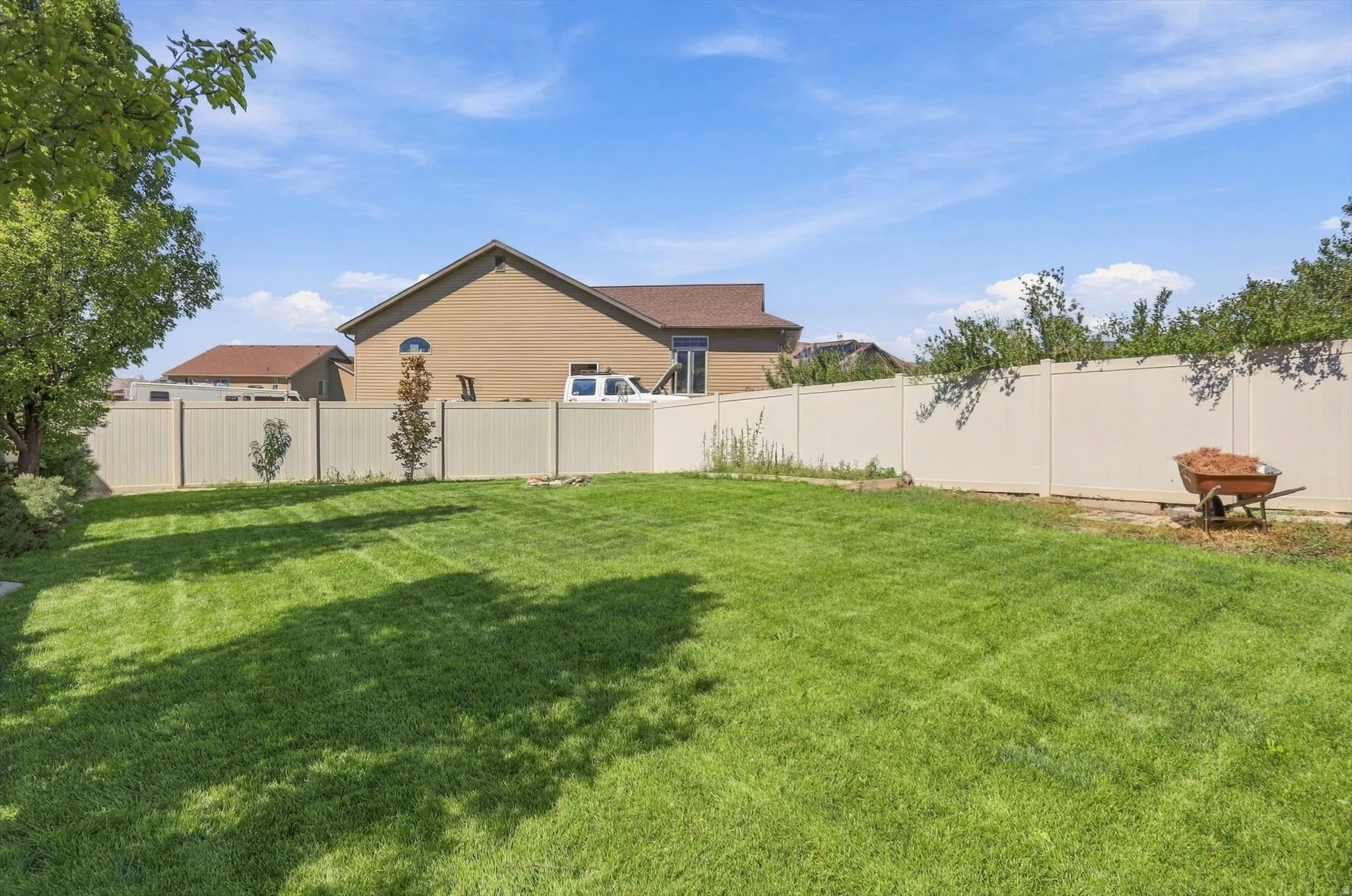 Expansive backyard featuring a manicured lawn and a privacy fence
