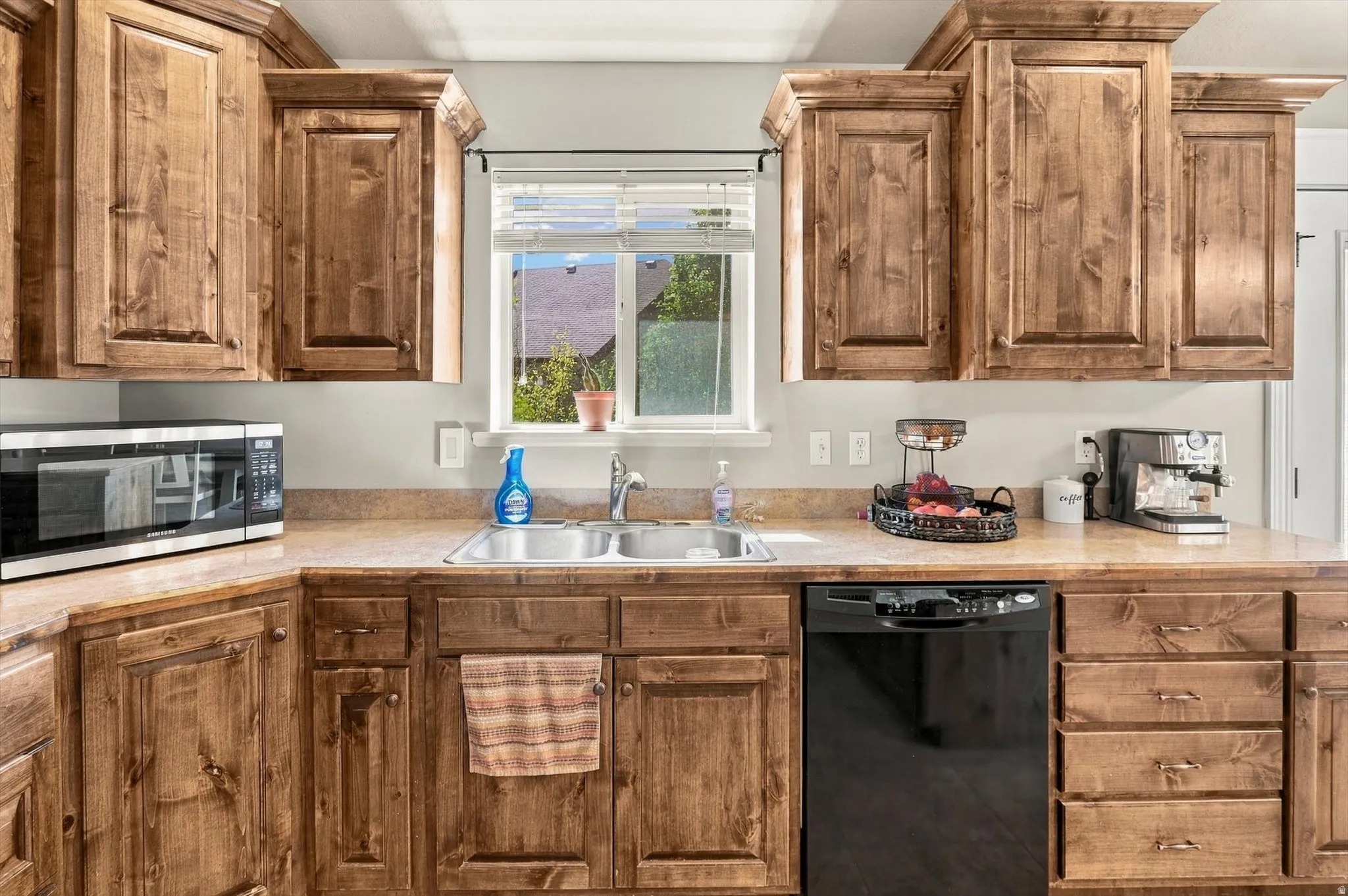 Kitchen featuring wood cabinetry, a double basin sink, and a black dishwasher