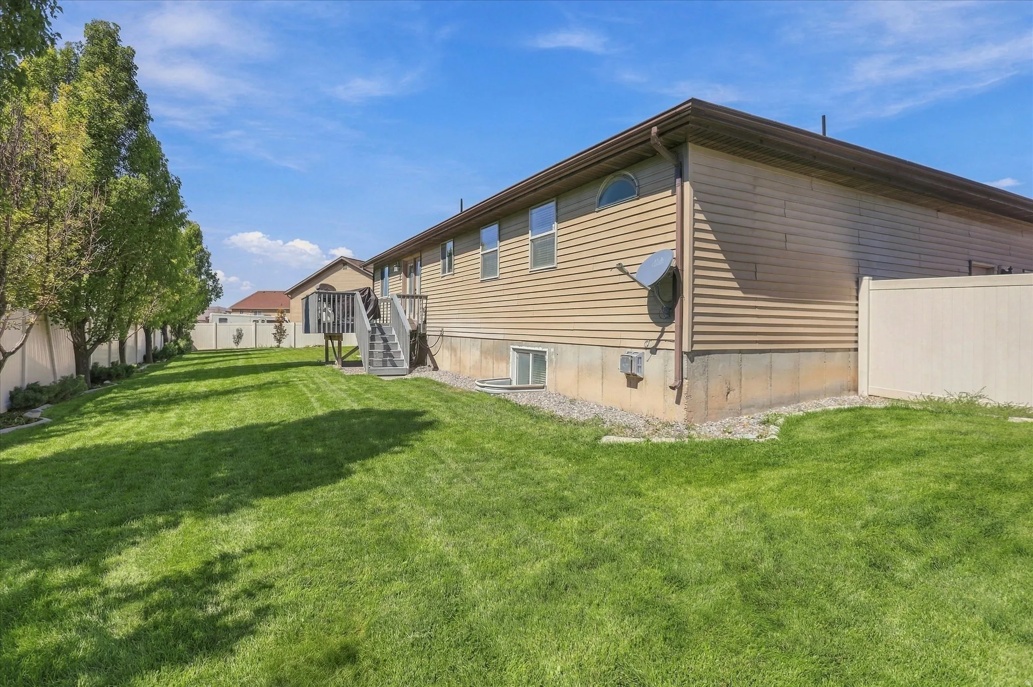 Expansive grassy yard with mature trees along a privacy fence