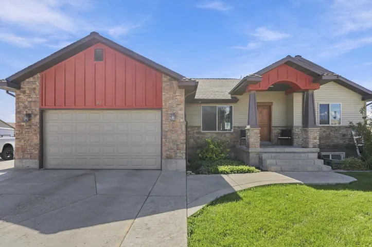 Stone veneer and siding exterior with a covered entry, wood door, and an attached two-car garage