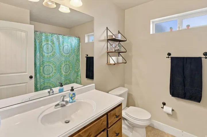 Bathroom featuring a wood-finish vanity with a white countertop, built-in sink, and overhead light fixture