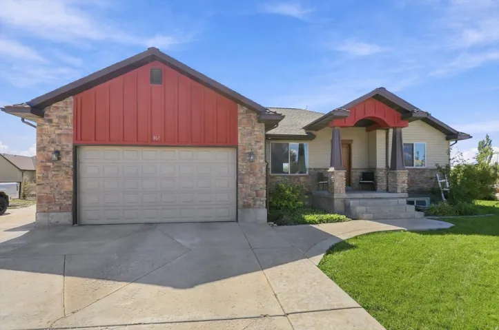 Stone and siding exterior with a covered entry, attached garage, and concrete driveway