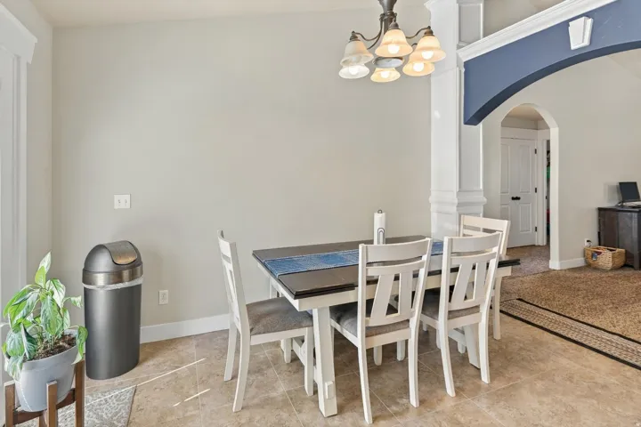 Tiled flooring, arched doorway, decorative column, and a multi-light chandelier