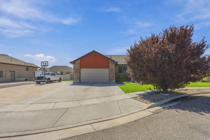 Stone and siding exterior with an attached garage, concrete driveway, and mature landscaping