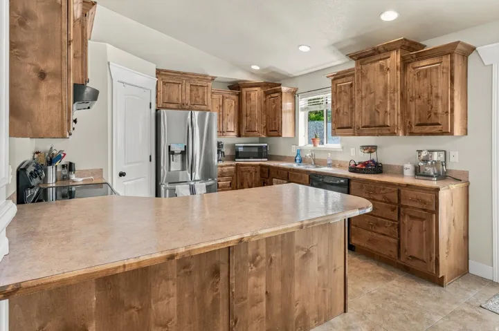 Kitchen featuring wood cabinetry, stainless steel appliances, a center island with countertop seating, and tile flooring