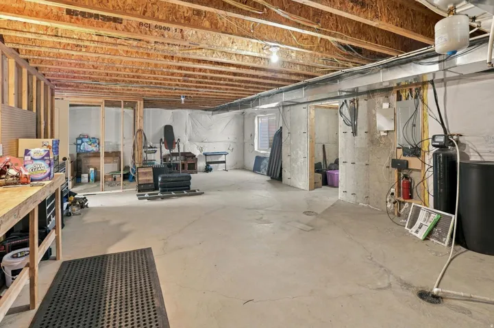 Unfinished basement with exposed ceiling joists and concrete flooring