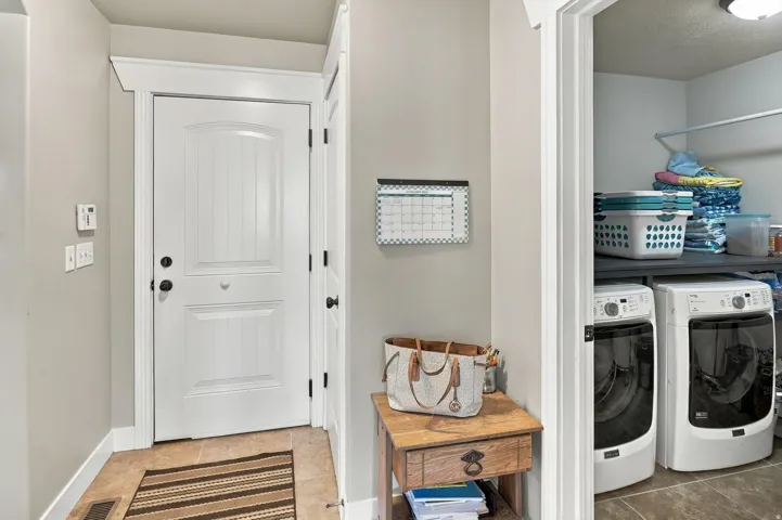 Panel door with dark hardware, tile flooring, and a dedicated laundry area with built-in shelving