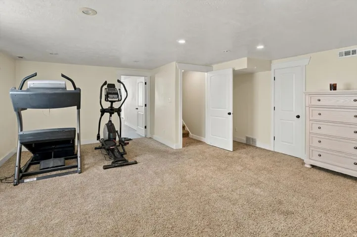 Carpeted recreation room with recessed lighting, multiple white paneled doors, and painted walls