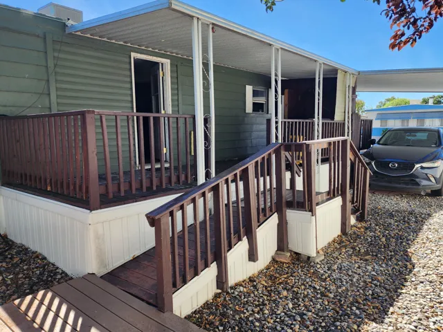 Covered front porch with wood railings and steps, green horizontal siding, and a gravel driveway