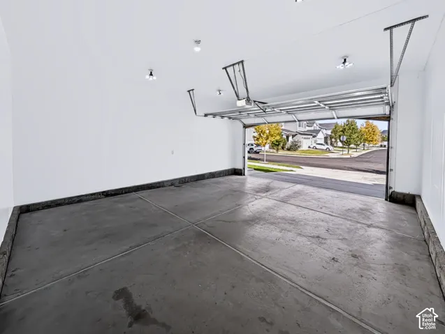Finished garage space with an overhead door, smooth concrete flooring, and ceiling-mounted lighting