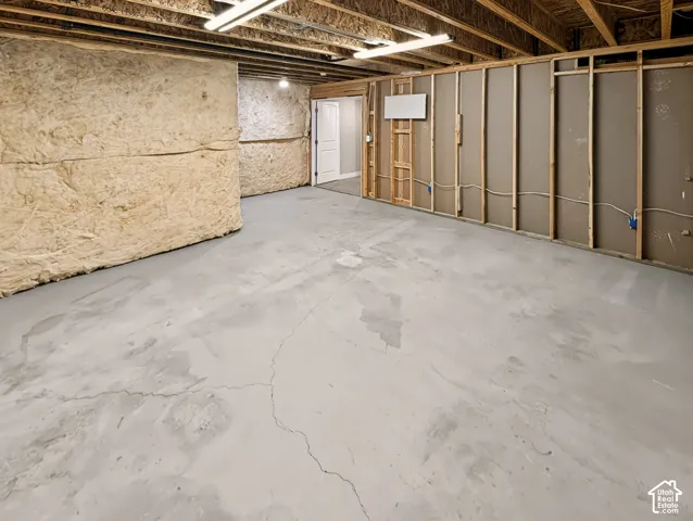 Unfinished basement featuring exposed wood joists, concrete flooring, and insulated walls
