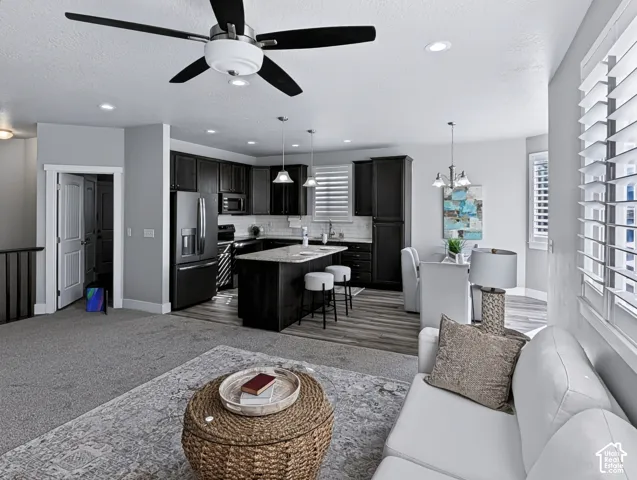 Open-concept living space featuring a ceiling fan, recessed lighting, wood-finish flooring, and plantation shutters