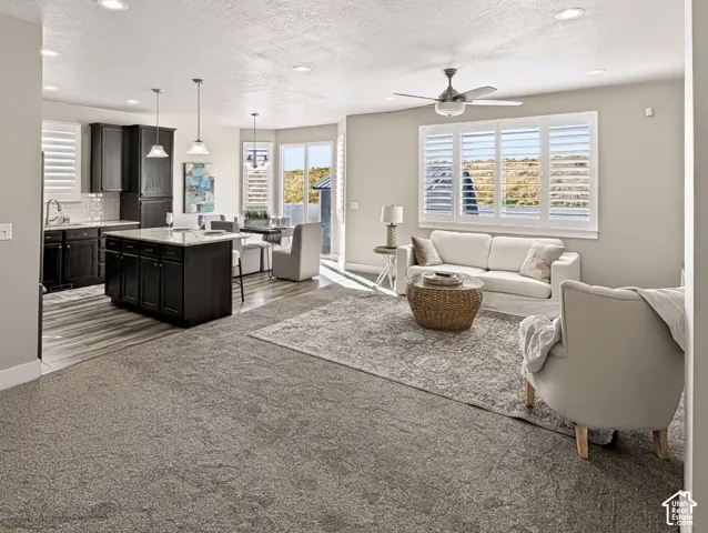 Open-concept living space featuring wood-finish flooring, dark cabinetry, recessed lighting, and a ceiling fan