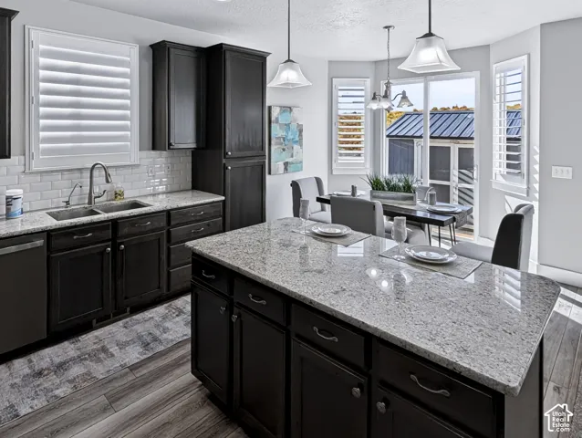 Kitchen featuring dark wood cabinetry, light-toned countertops, subway tile backsplash, and wood-finish flooring