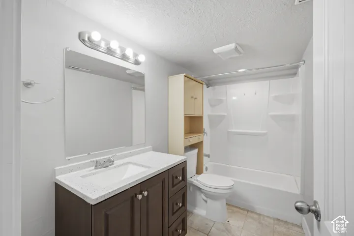 Bathroom featuring a dark wood-finish vanity, white countertop with integrated sink, chrome faucet, and a combination tub/shower with a white surround