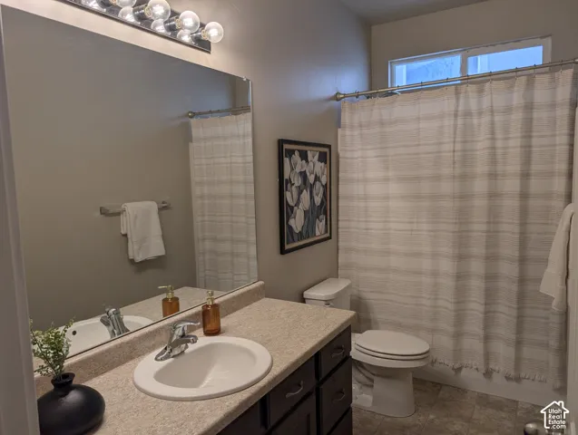 Bathroom featuring a single vanity with built-in sink, chrome fixtures, and a vanity light bar