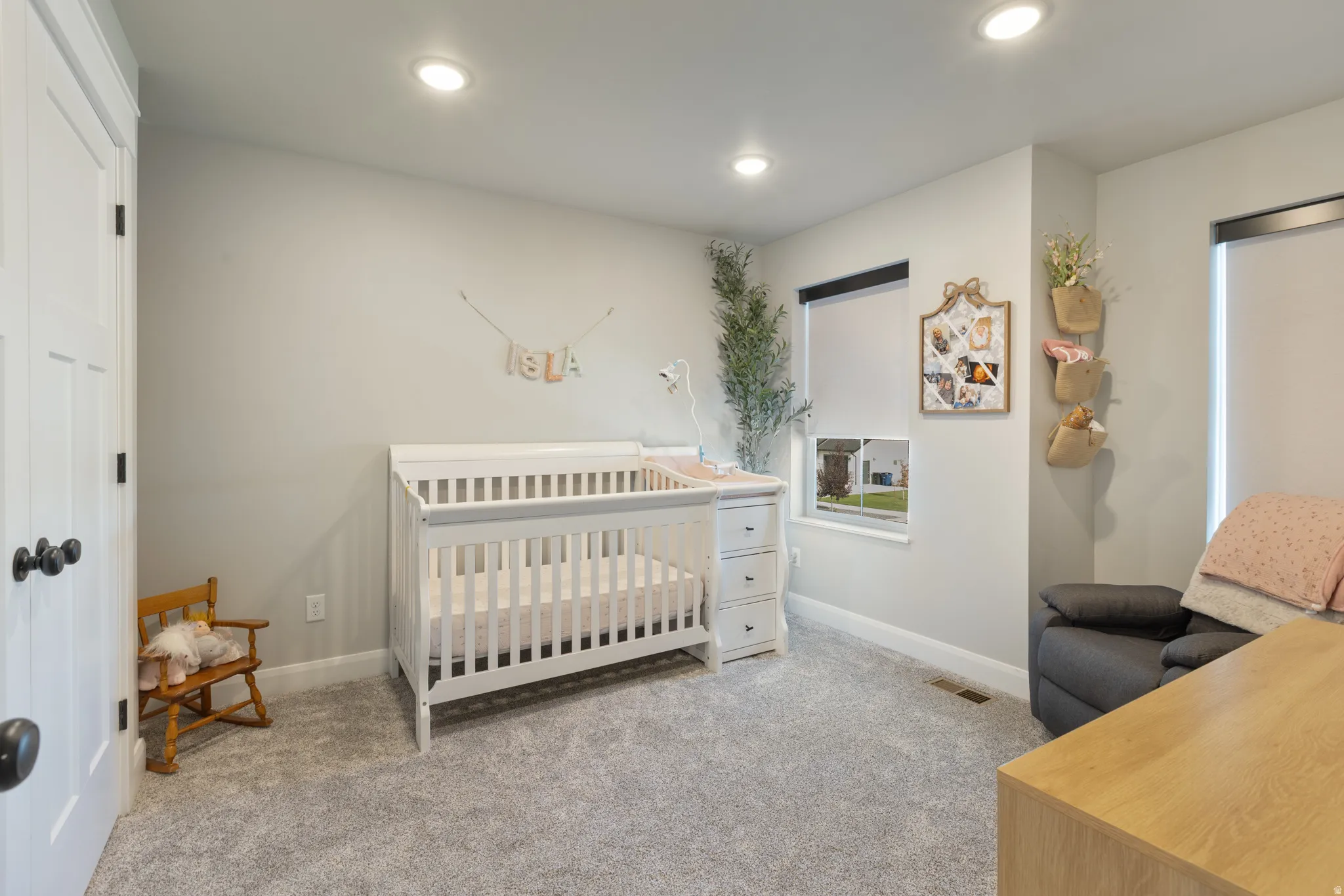 Recessed lighting illuminates a carpeted room with multiple windows, paneled doors, and white trim