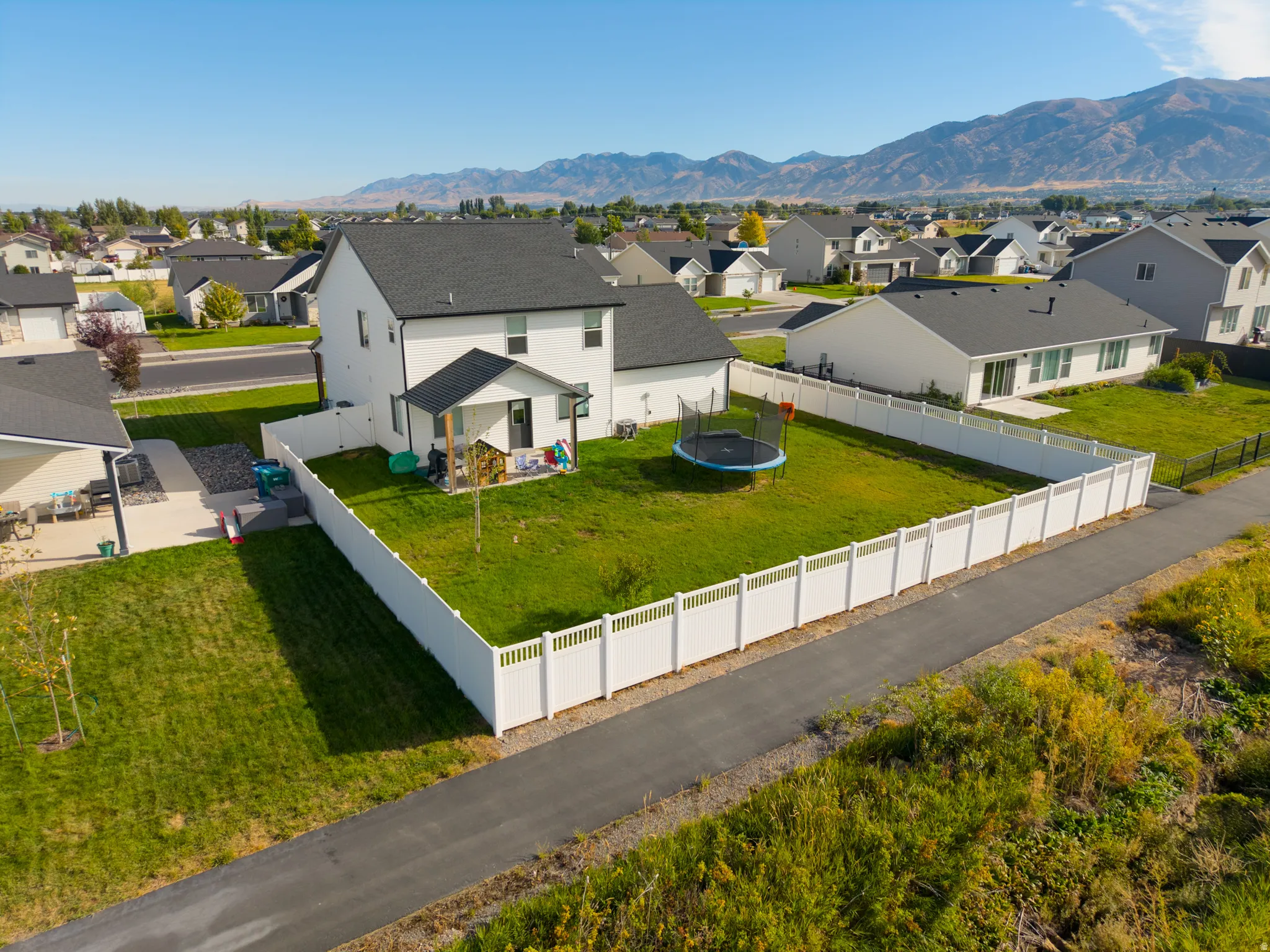 Expansive backyard with a white privacy fence, offering a verdant lawn and a mountain backdrop