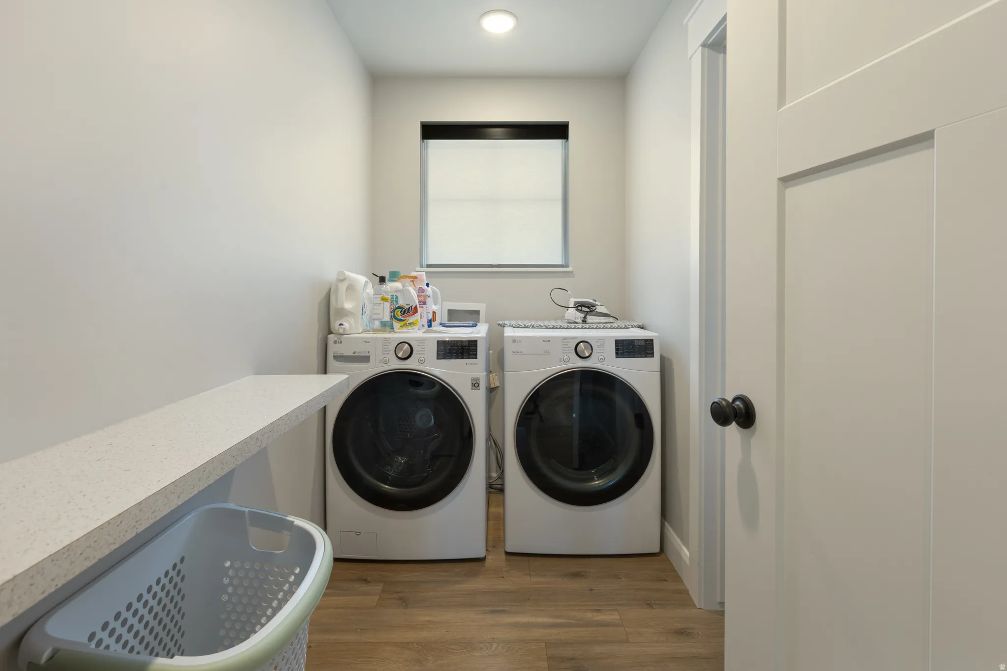 Dedicated laundry space featuring wood-finish flooring, a built-in counter, and recessed lighting