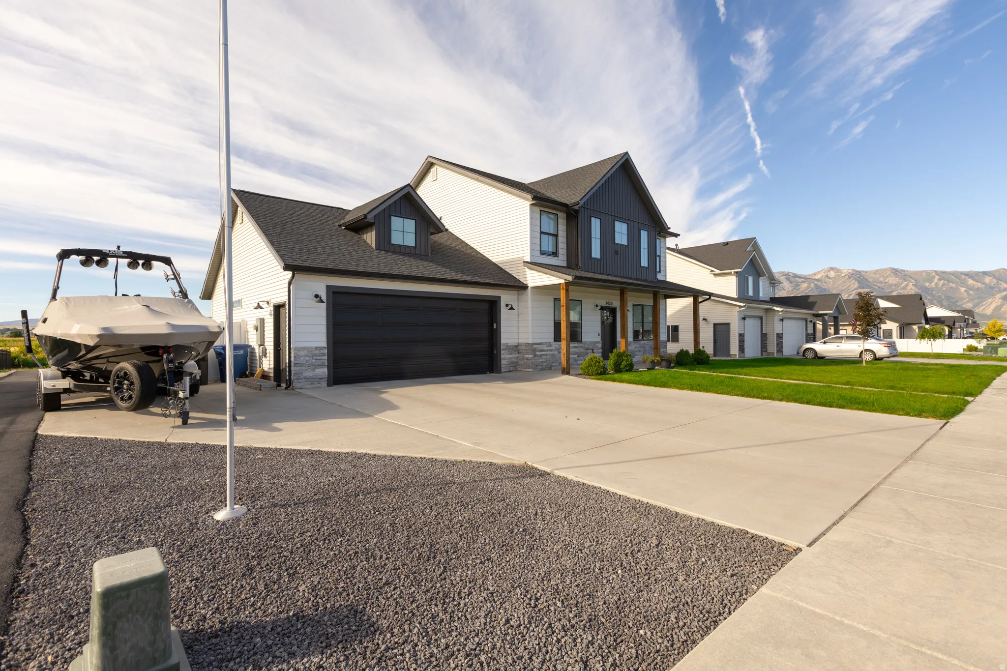 Two-story residence with a dark shingle roof, light-colored siding, and a two-car garage with a dark door