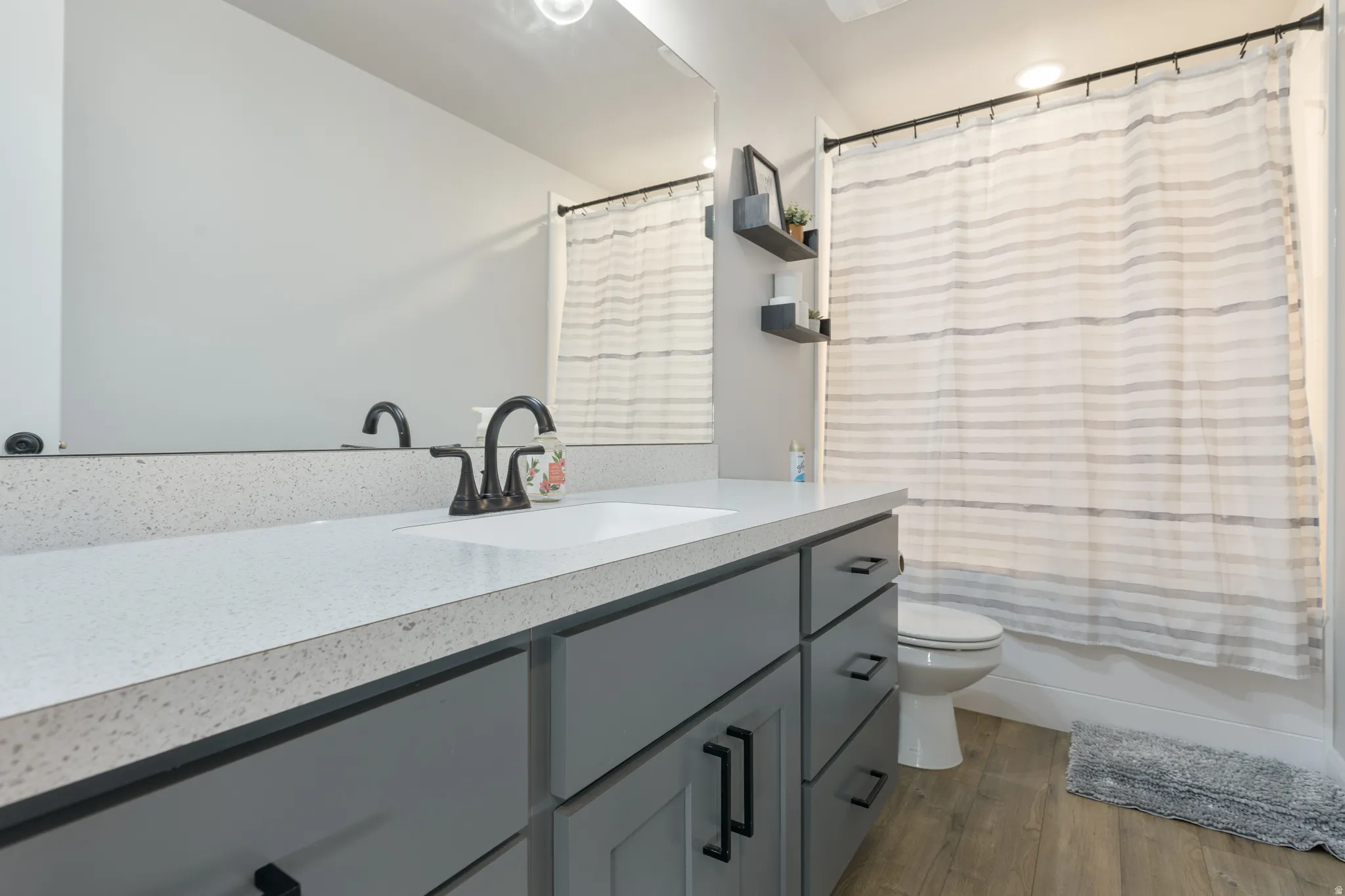 Spacious vanity with a light-toned countertop, gray cabinetry, and dark hardware