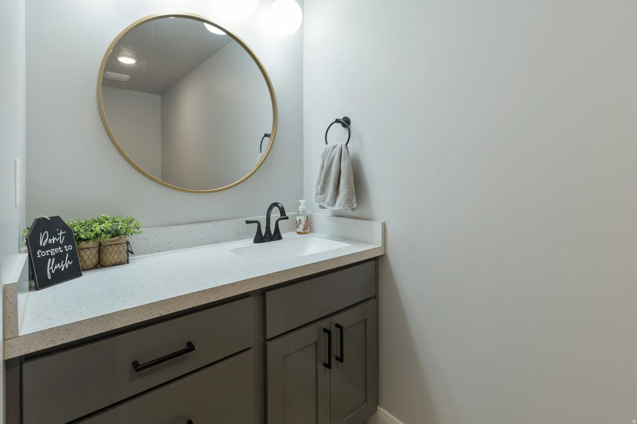 Vanity featuring a light-colored countertop, integrated sink, dark cabinetry, and matte black hardware