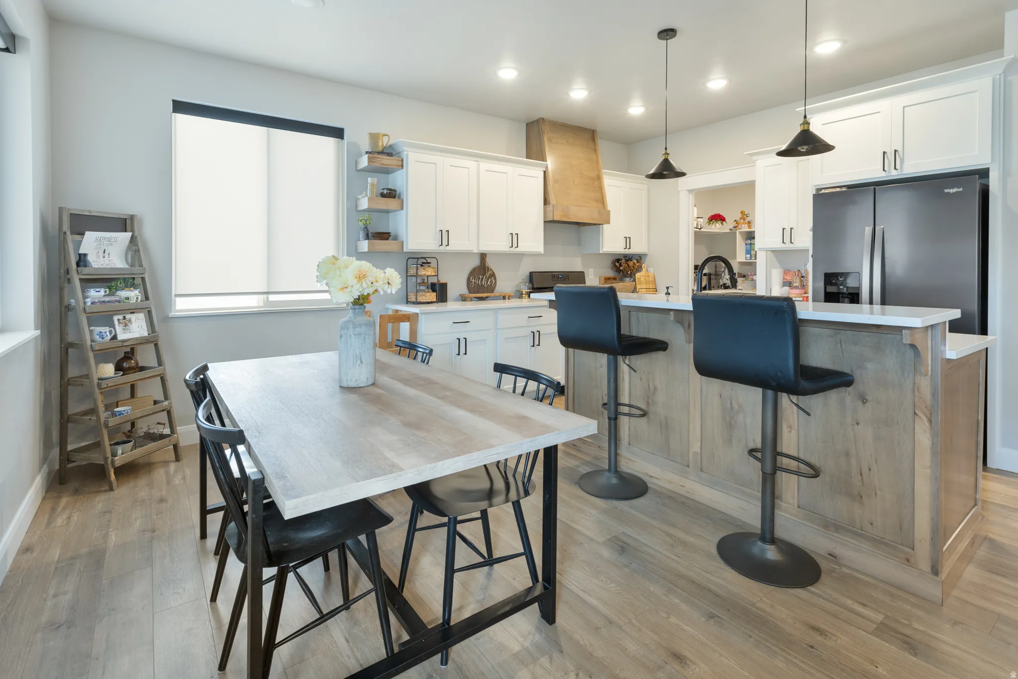 Kitchen featuring wood-finish flooring, white cabinetry, a kitchen island with seating, a built-in refrigerator, and recessed lighting
