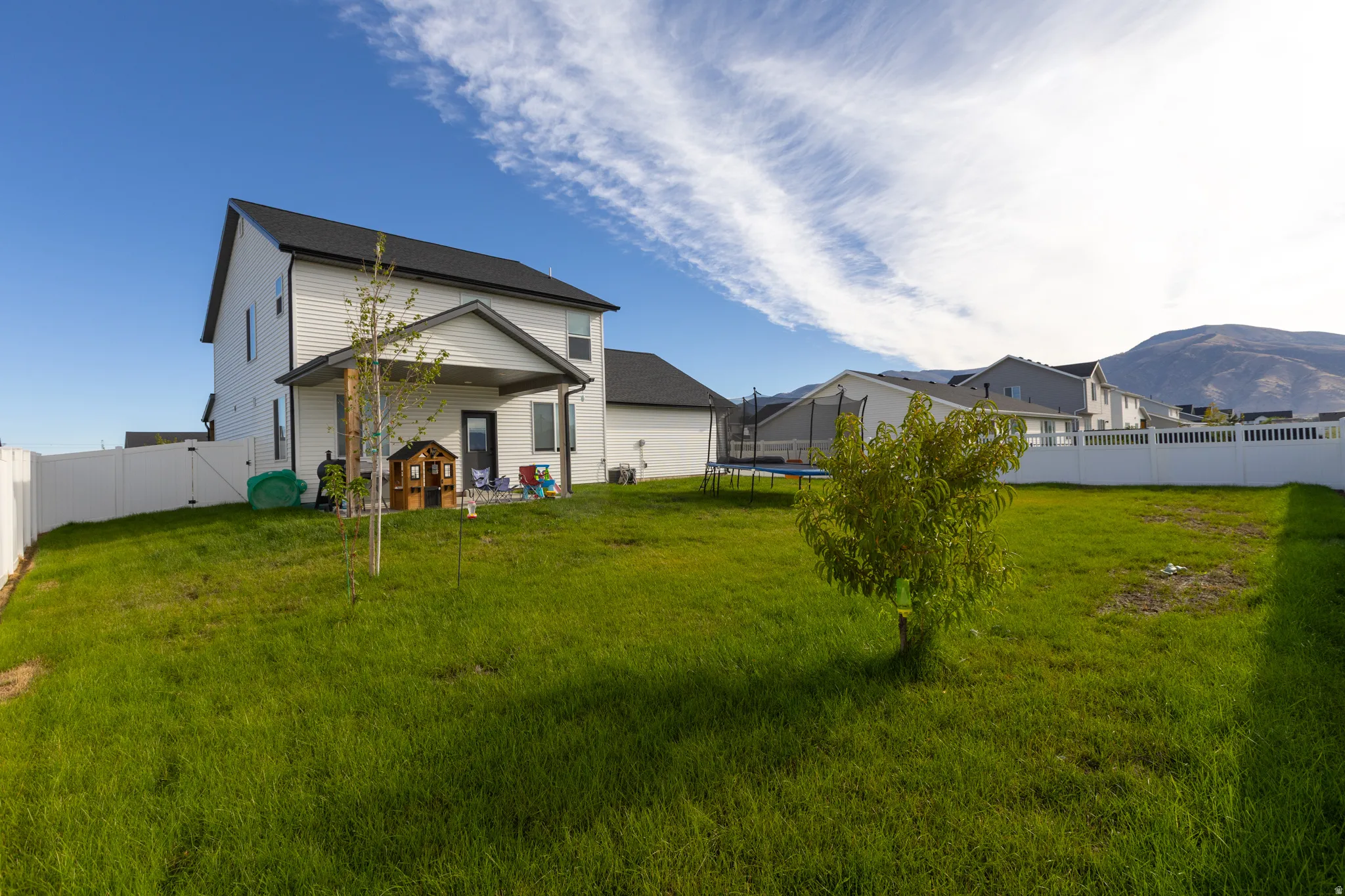 Expansive green lawn with a white privacy fence
