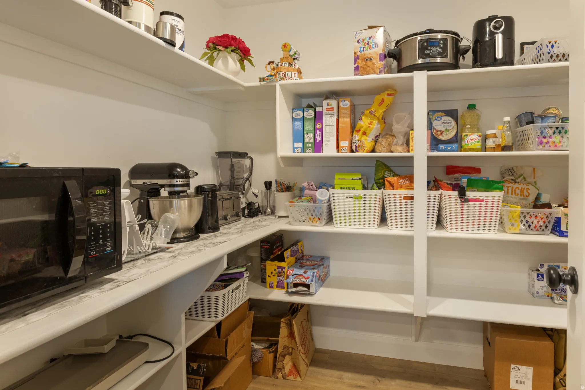 Built-in pantry shelving with a corner countertop and wood-finish flooring