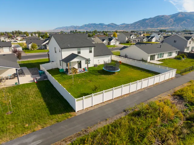 Expansive backyard with a white privacy fence, offering a verdant lawn and a mountain backdrop