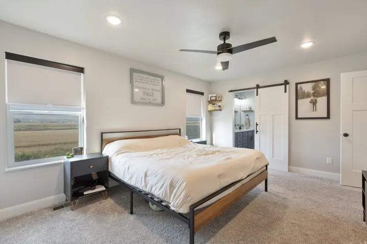 Recessed lighting, ceiling fan with light, barn door entry, window with roller shade, and carpet flooring