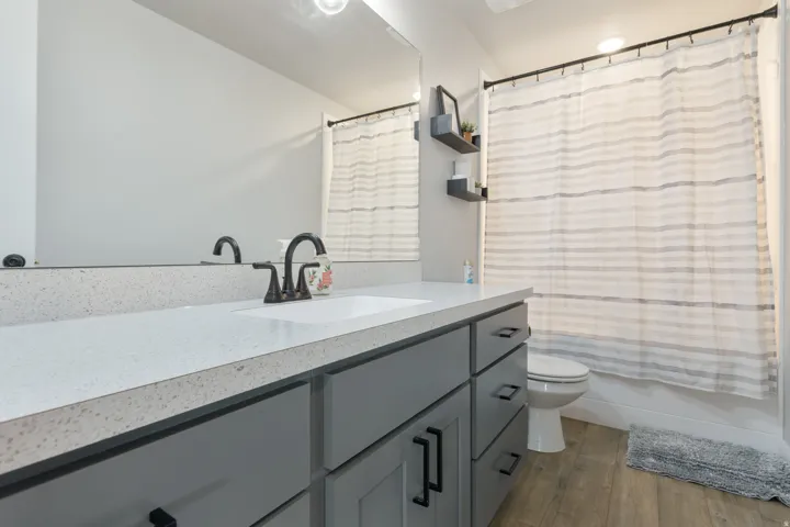 Spacious vanity with a light-toned countertop, gray cabinetry, and dark hardware